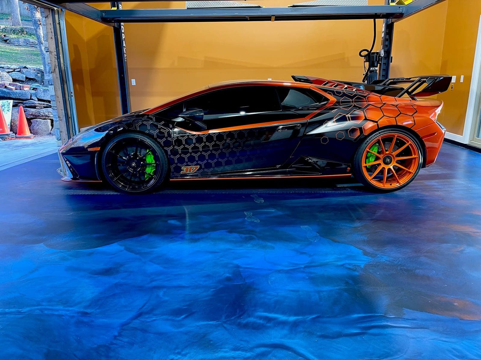 Showroom garage with a deep blue metallic floor beneath a sports car