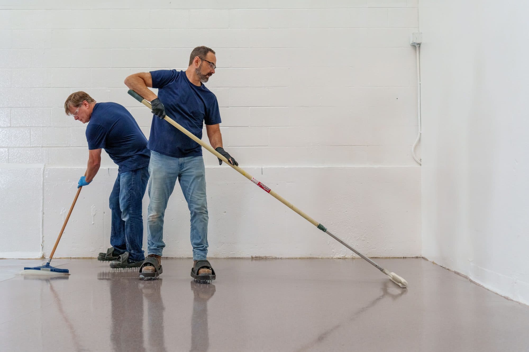 Two Polymer Nation installers spreading and backrolling a Scapes floor